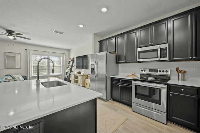 kitchen featuring appliances with stainless steel finishes, light countertops, visible vents, and a sink