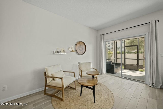 sitting room with a textured ceiling, baseboards, and wood tiled floor