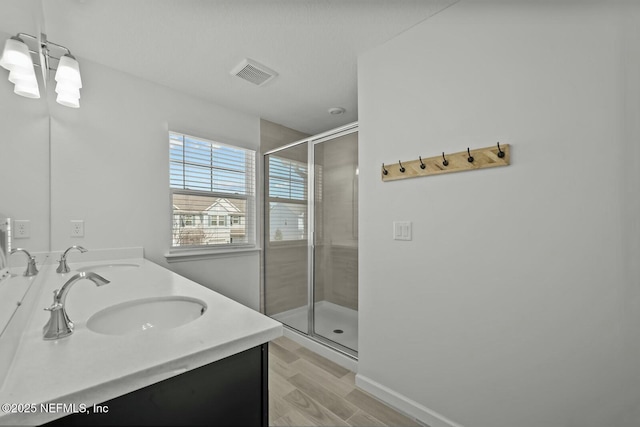 bathroom with a stall shower, visible vents, a sink, and double vanity