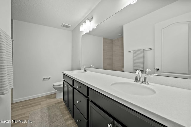 bathroom with toilet, a sink, visible vents, and wood tiled floor