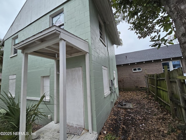 view of side of property with concrete block siding and fence