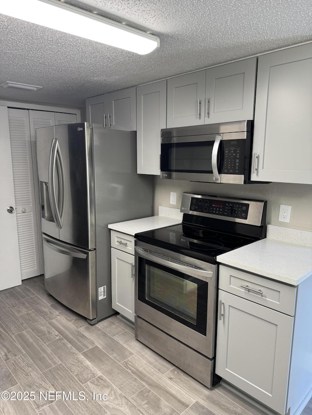 kitchen with stainless steel appliances, light countertops, and wood tiled floor