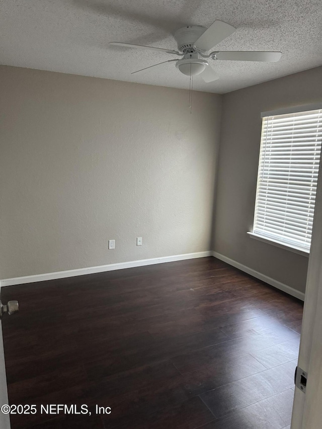 spare room featuring dark wood-style floors, a ceiling fan, baseboards, and a textured ceiling