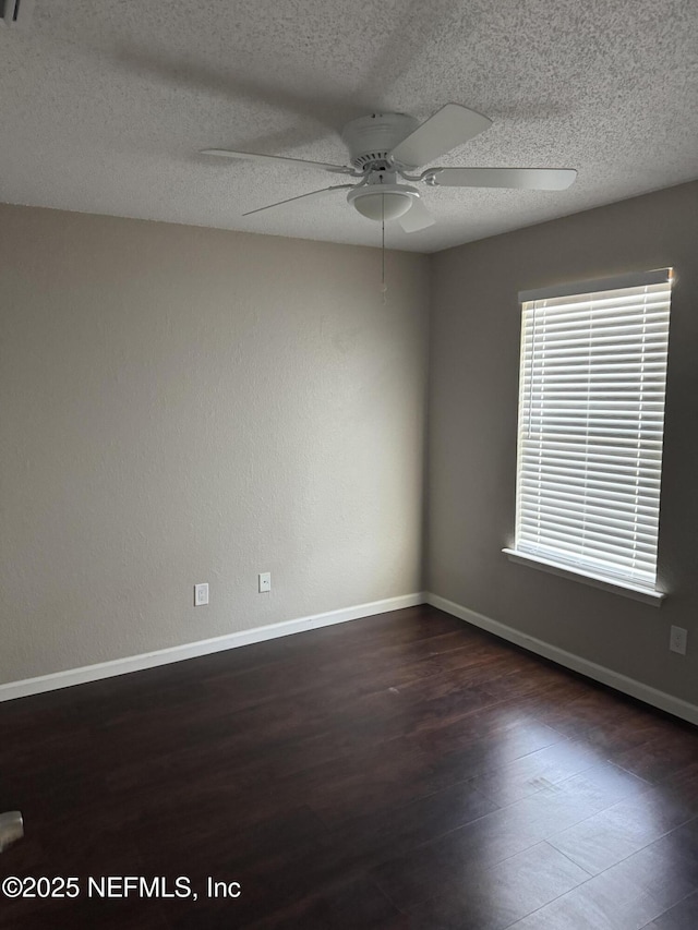 spare room with dark wood-style flooring, ceiling fan, a textured ceiling, and baseboards