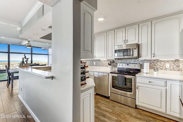 kitchen featuring appliances with stainless steel finishes, light countertops, backsplash, and white cabinetry