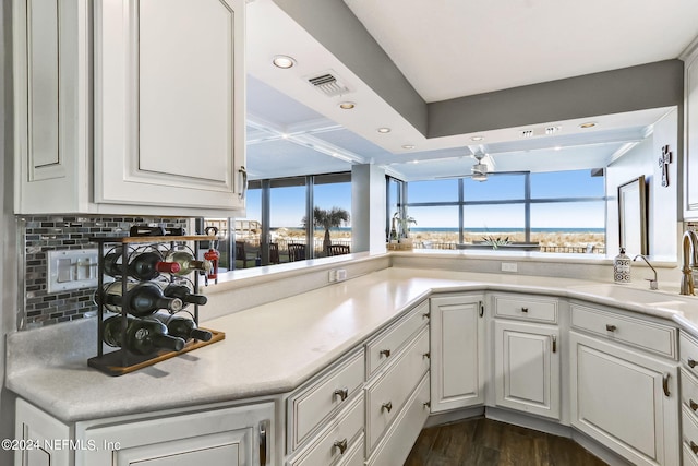 kitchen with tasteful backsplash, light countertops, a sink, and white cabinetry