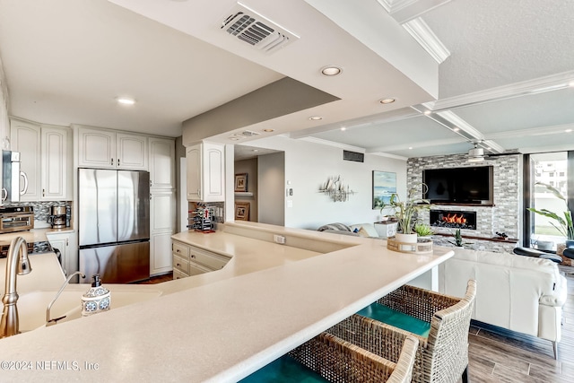 kitchen with visible vents, open floor plan, stainless steel appliances, light countertops, and a fireplace