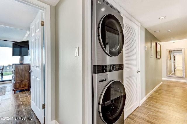 washroom with stacked washer and dryer, laundry area, baseboards, wood tiled floor, and recessed lighting