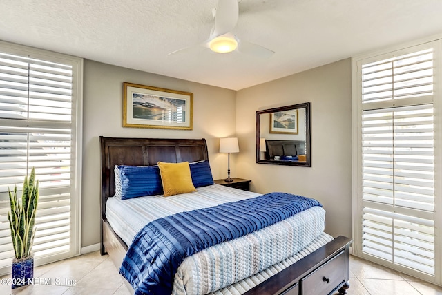 bedroom with ceiling fan, a textured ceiling, and light tile patterned floors