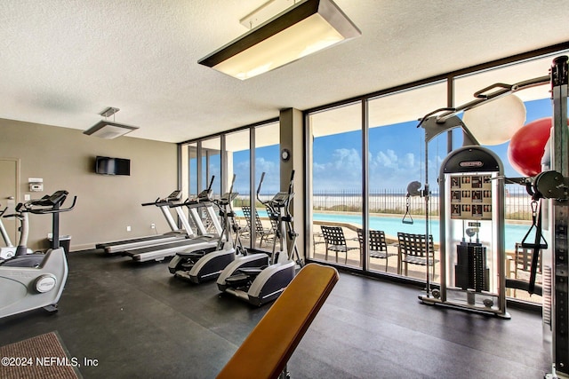 exercise room featuring a wall of windows, a textured ceiling, and baseboards