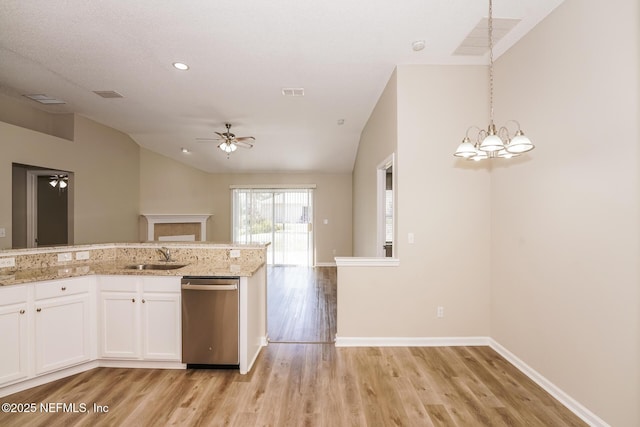 kitchen featuring pendant lighting, stainless steel dishwasher, white cabinets, vaulted ceiling, and a sink