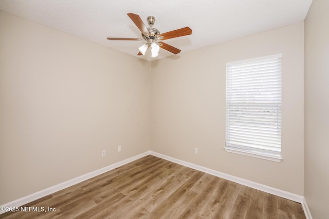 empty room featuring a ceiling fan, baseboards, and wood finished floors