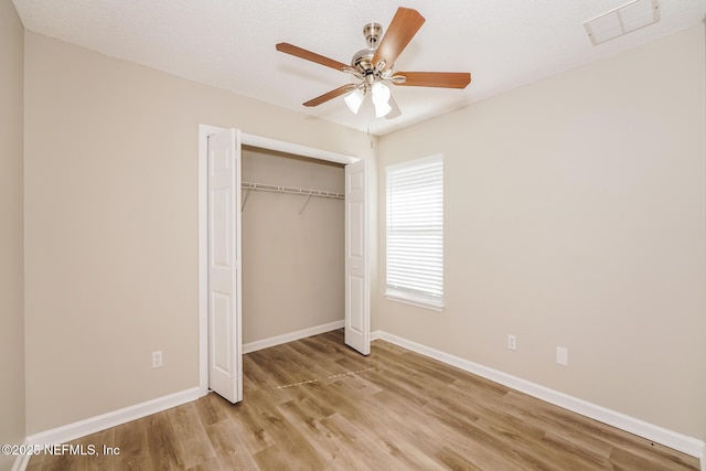 unfurnished bedroom featuring baseboards, visible vents, a ceiling fan, light wood-style floors, and a closet