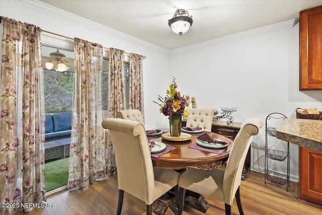 dining area featuring a textured ceiling, ornamental molding, and wood finished floors