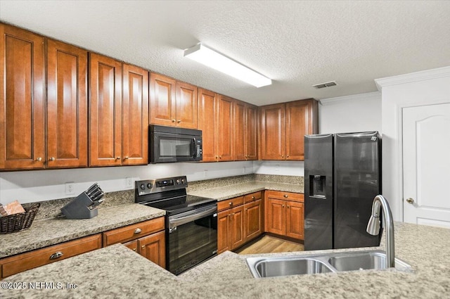 kitchen with black microwave, visible vents, stainless steel electric range oven, refrigerator with ice dispenser, and a sink