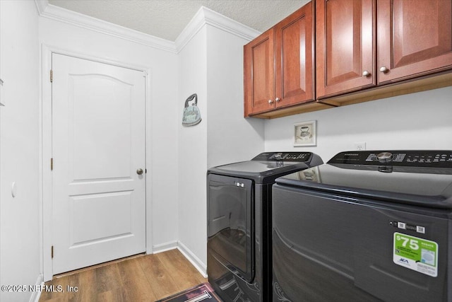 washroom with cabinet space, washer and clothes dryer, ornamental molding, wood finished floors, and a textured ceiling