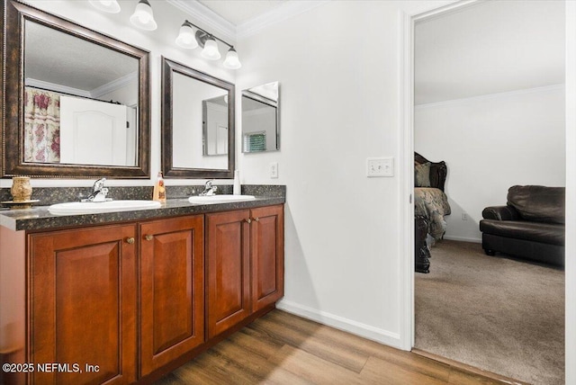 bathroom featuring double vanity, crown molding, a sink, and wood finished floors