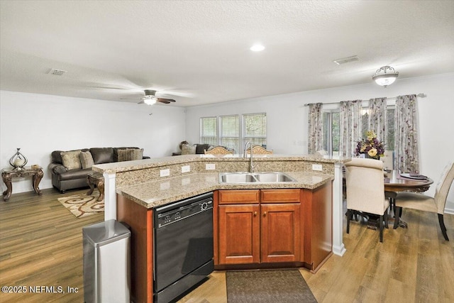 kitchen featuring dishwasher, open floor plan, a sink, and light wood-style floors