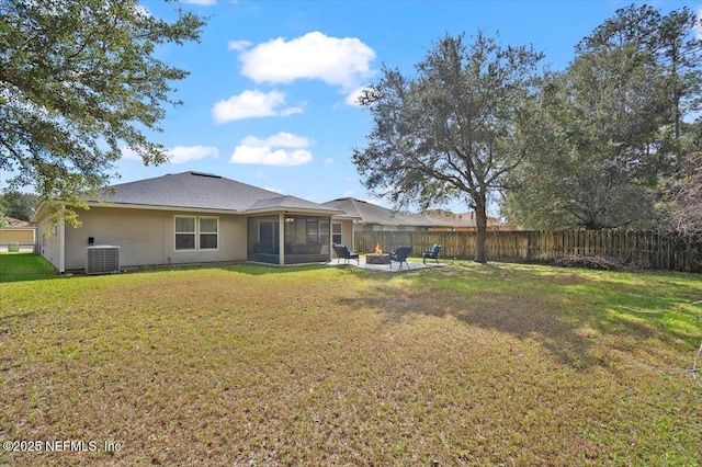 rear view of house with a fire pit, a sunroom, fence, cooling unit, and a yard