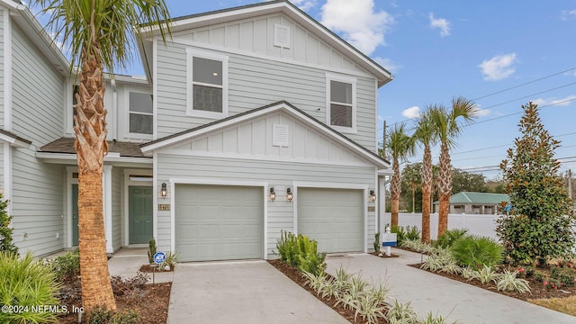 traditional-style house with a garage, concrete driveway, board and batten siding, and fence