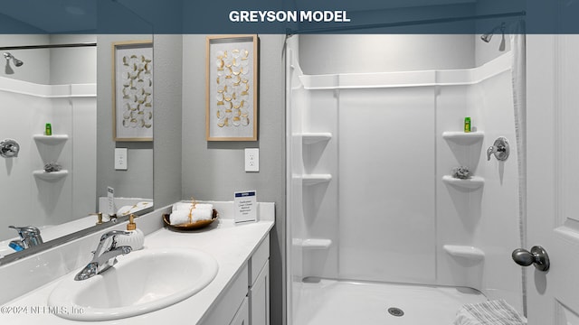 bathroom featuring a textured wall, a shower, and vanity