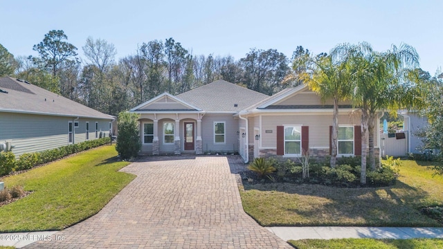 view of front of property with stone siding, a front lawn, and decorative driveway