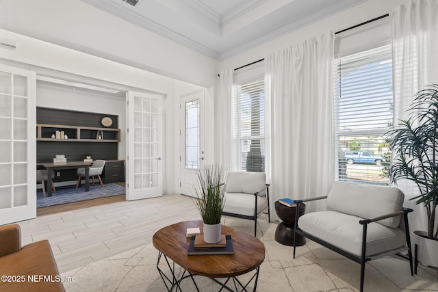 living area with light wood-style floors, a tray ceiling, french doors, and crown molding