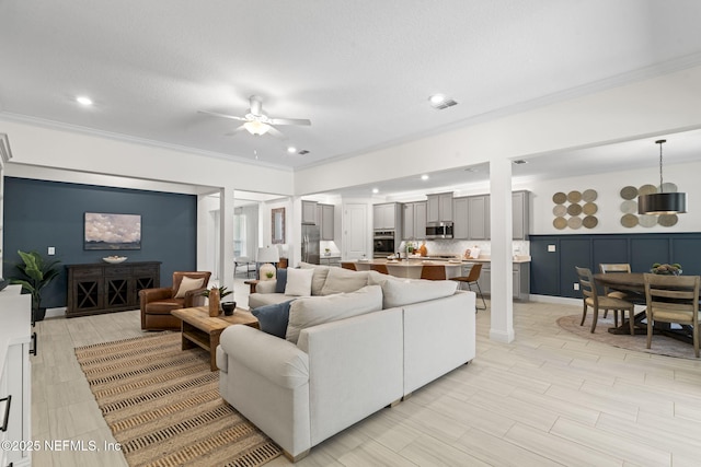 living room with ceiling fan, recessed lighting, visible vents, and crown molding