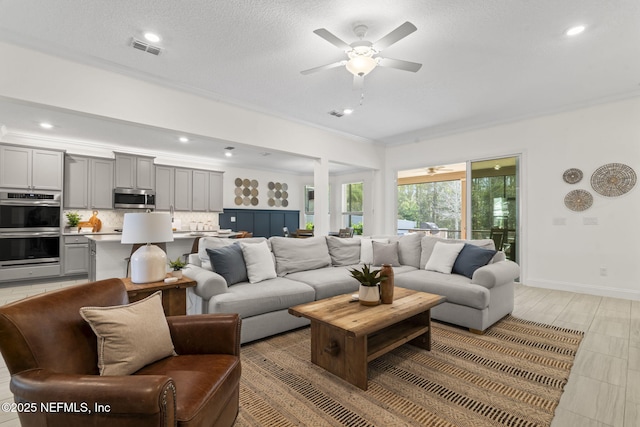 living area with crown molding, recessed lighting, visible vents, a ceiling fan, and baseboards