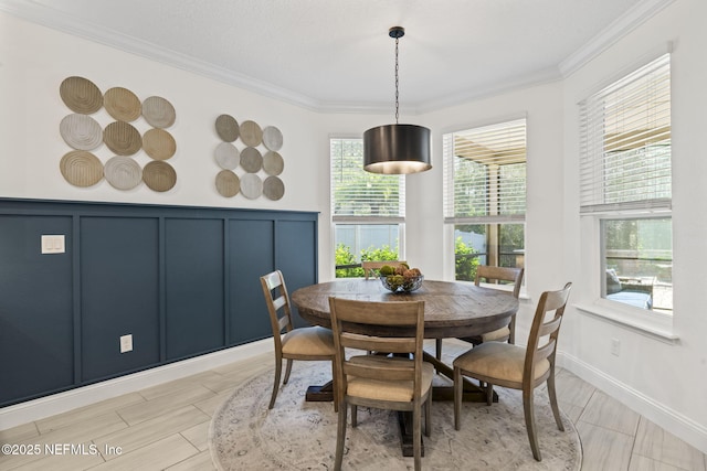 dining space with ornamental molding and a decorative wall