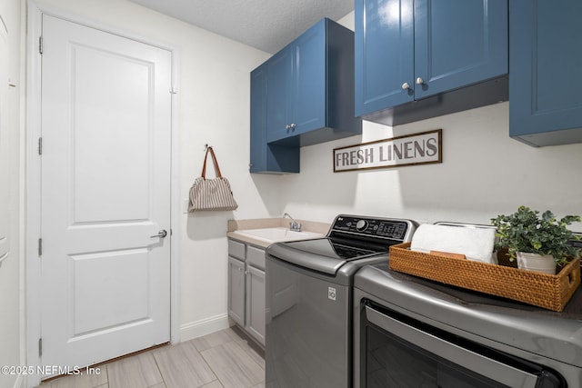 laundry area with a textured ceiling, a sink, baseboards, washer and dryer, and cabinet space