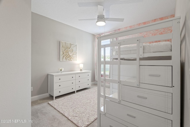 bedroom featuring light carpet, ceiling fan, baseboards, and a textured ceiling