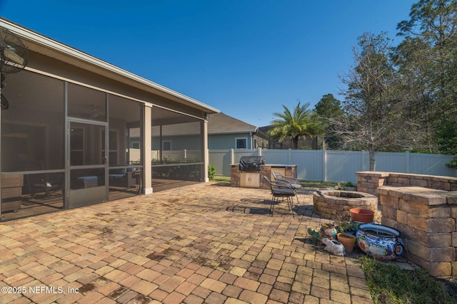 view of patio featuring an outdoor fire pit, area for grilling, a fenced backyard, and a sunroom