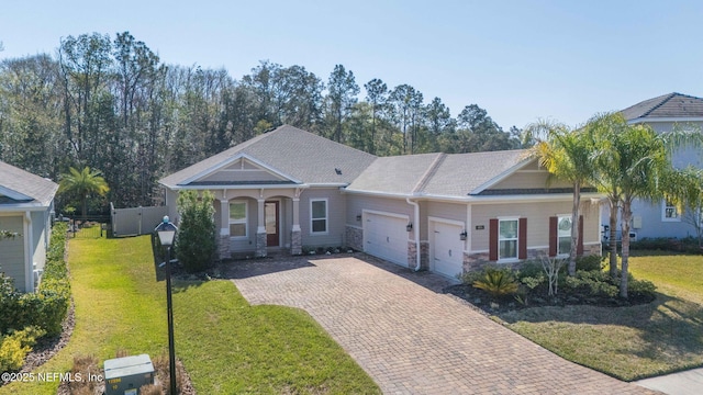 view of front of property with decorative driveway, a front yard, fence, a garage, and stone siding