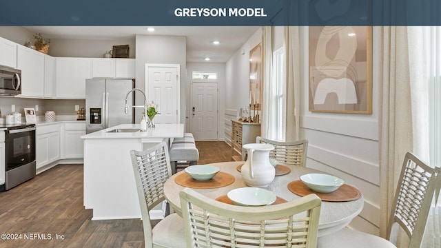 kitchen with a sink, white cabinetry, light countertops, appliances with stainless steel finishes, and dark wood finished floors