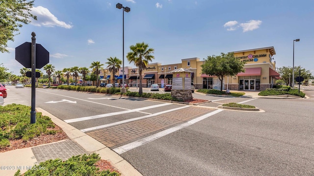 view of road featuring street lights, curbs, traffic signs, and sidewalks