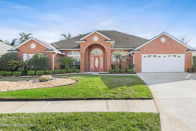 view of front facade with concrete driveway, roof with shingles, an attached garage, a front lawn, and brick siding