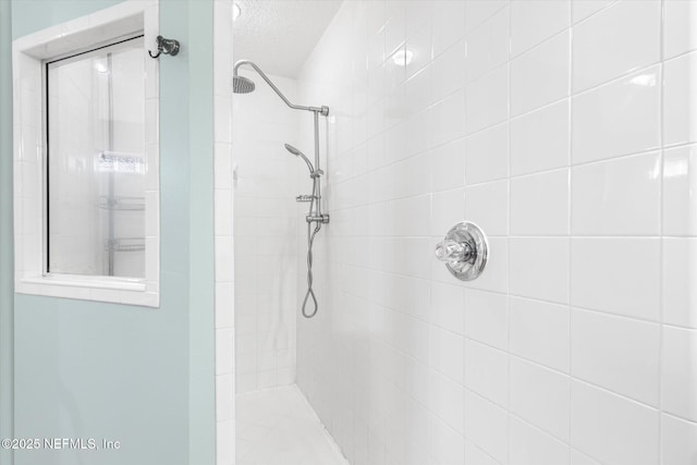 full bathroom featuring a textured ceiling and tiled shower