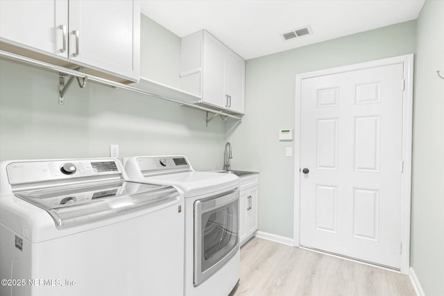 laundry room featuring visible vents, cabinet space, light wood-style floors, a sink, and washer and dryer