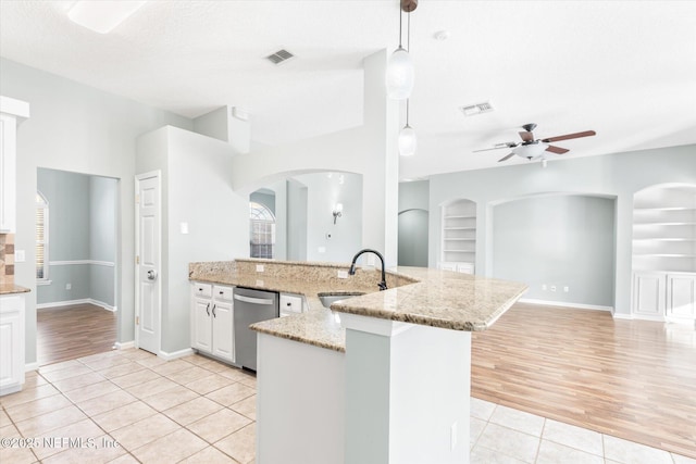 kitchen with visible vents, a sink, built in shelves, stainless steel dishwasher, and light tile patterned flooring