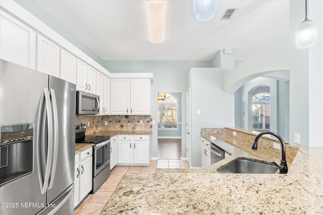 kitchen featuring stainless steel appliances, visible vents, backsplash, white cabinetry, and a sink