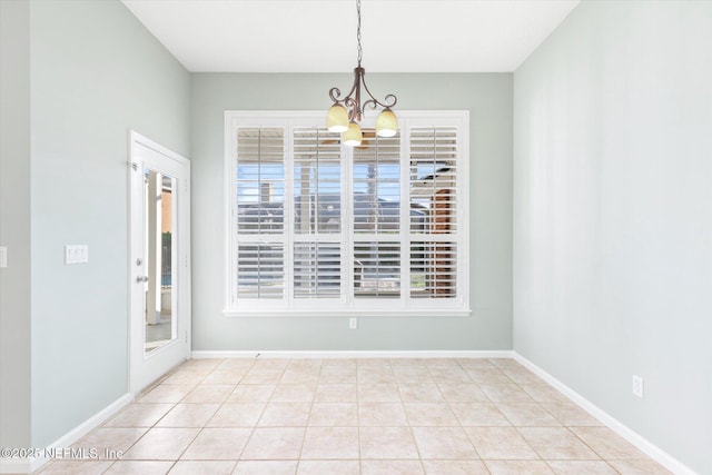 unfurnished dining area featuring a chandelier, baseboards, and light tile patterned floors