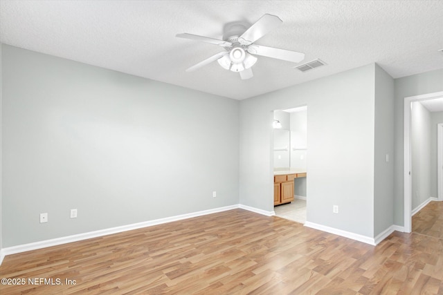 unfurnished bedroom featuring built in desk, visible vents, a textured ceiling, light wood-type flooring, and baseboards