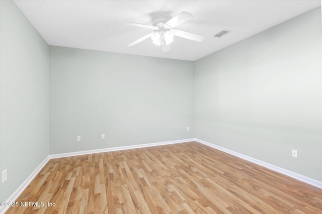 spare room featuring light wood-type flooring, visible vents, and baseboards