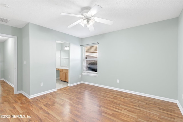 empty room featuring visible vents, baseboards, a ceiling fan, built in study area, and light wood-style flooring