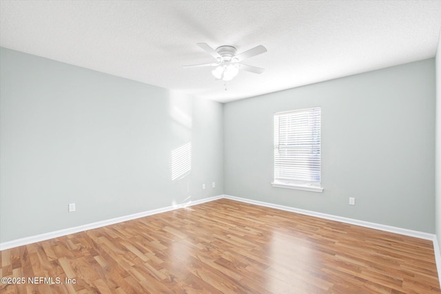 spare room with light wood-type flooring, ceiling fan, a textured ceiling, and baseboards