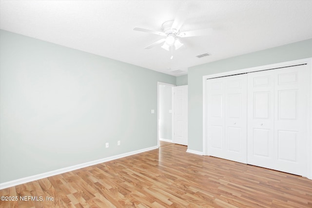 unfurnished bedroom featuring a ceiling fan, baseboards, visible vents, light wood-style floors, and a closet