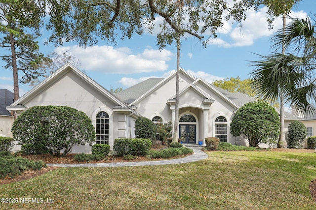 view of front facade with french doors, a front lawn, a shingled roof, and stucco siding