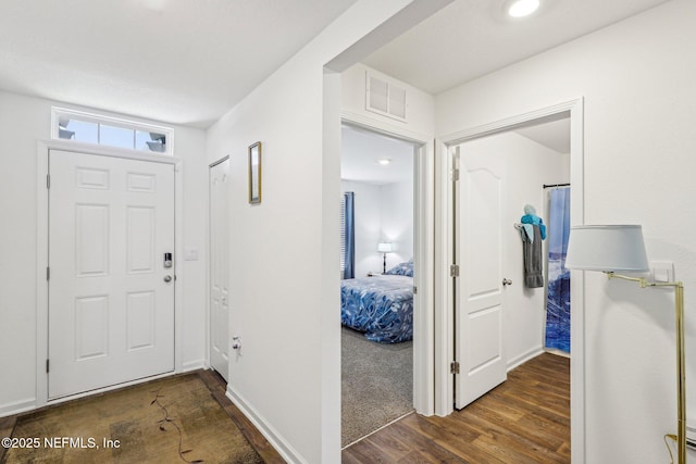 foyer featuring visible vents, baseboards, and wood finished floors