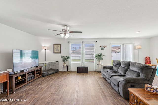 living area featuring ceiling fan, baseboards, and wood finished floors